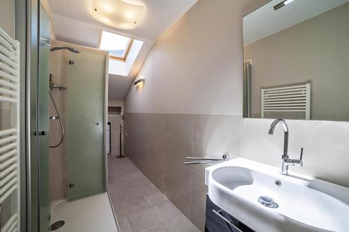 uma casa de banho com um lavatório, um chuveiro e um espelho. em Ferienwohnung Cuve em Merano