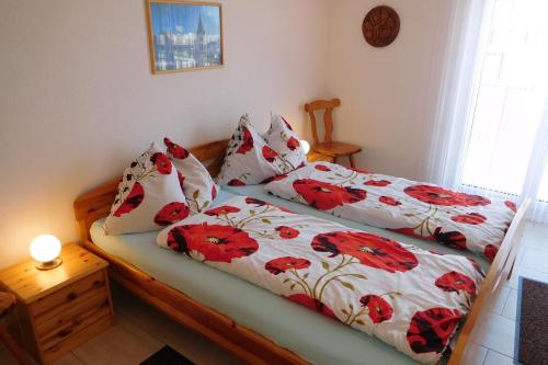 1 dormitorio con 2 camas con flores rojas en Haus Mezzaselva - CharmingStay, en Flumserberg