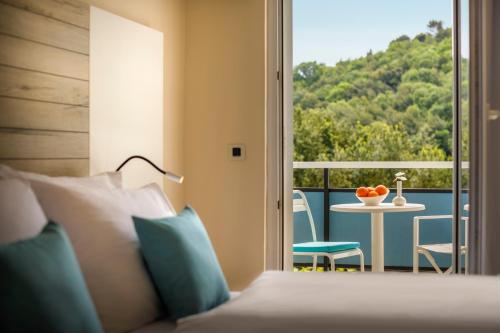 a bedroom with a bed and a balcony with a table at Hotel Marina - Liburnia in Mošćenička Draga