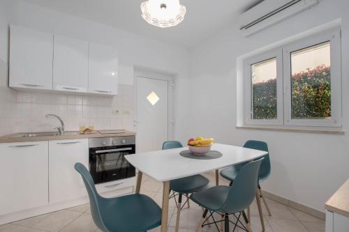 une cuisine avec une table blanche et des chaises bleues dans l'établissement Apartment Lucija, Stinjan, à Pula