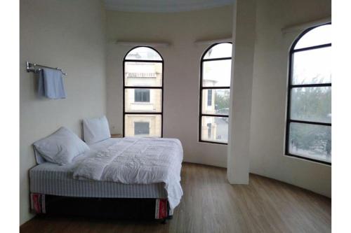 een slaapkamer met een bed en 3 ramen bij RedDoorz @ Komplek MMTC Deli Serdang in Pulauberayan Dadap