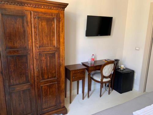 a bedroom with a desk and a large wooden cabinet at Relais Real Collegio in Noli