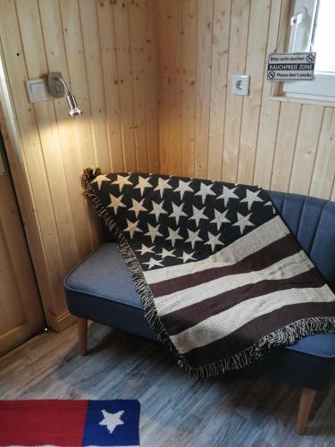 eine blaue Couch mit einer amerikanischen Flaggendecke drauf in der Unterkunft Schäferwagen Grünspecht in Ratingen
