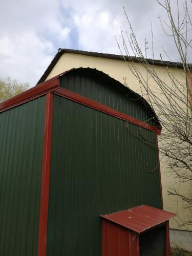 ein großes grünes Gebäude mit rotem Dach in der Unterkunft Schäferwagen Grünspecht in Ratingen