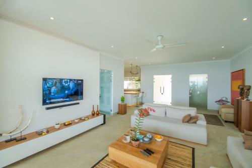 a living room with a couch and a tv on a wall at Deep Blue Villa Bali in Umeanyar