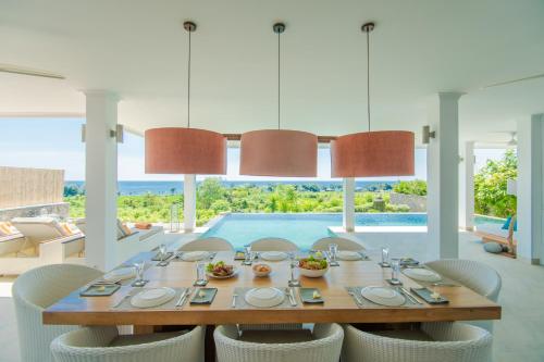 a dining room with a table and chairs and a pool at Deep Blue Villa Bali in Umeanyar