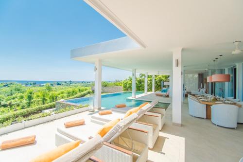 an open living room with white furniture and a swimming pool at Deep Blue Villa Bali in Umeanyar