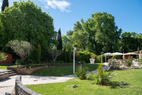 a garden with trees and grass and a fence at Novotel Aix-en-Provence Pont de L'Arc in Aix-en-Provence