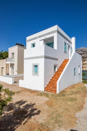 a white house with orange stairs on a hill at THE SHIP in Lefkos Karpathou