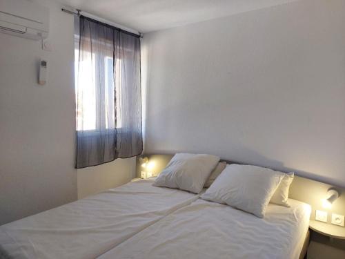 un lit blanc dans une chambre avec une fenêtre dans l'établissement Magnifique et Moderne T2 avec vue imprenable sur les Albères Turquoise 134, à Canet