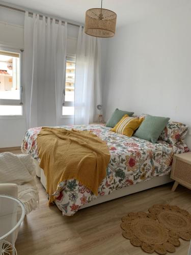 PERLA DEL SOL في توريمولينوس: غرفة نوم مع سرير مع لحاف متهالك