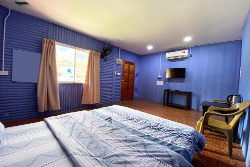 a blue bedroom with a bed and a window at Hotel O Kampung Stay Kilimu in Ranau