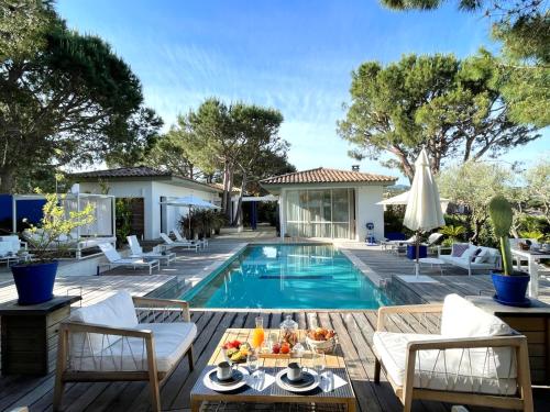 a patio with a pool and chairs and a table with fruit on it at Les Suites d'Agosta in Porticcio