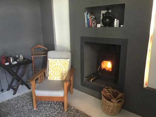 a living room with a chair and a fireplace at Annis Nest in Riebeek-Kasteel