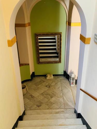 a hallway with green walls and a window and a tile floor at Relais Real Collegio in Noli