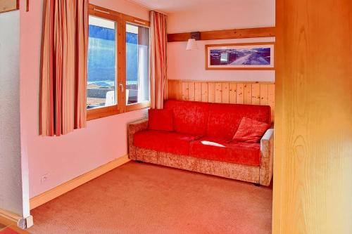 a red couch in a room with a window at Apartment Near The Slopes La Plagne in La Plagne