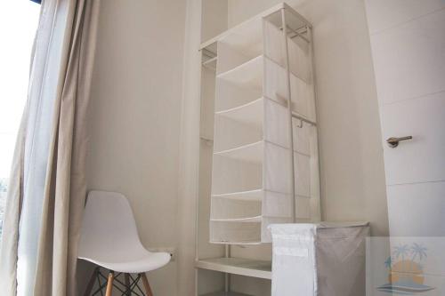 Un armario blanco con una silla blanca en una habitación en 1minuto del mar ,vistas, Playa tranquila. Adaptado en Benajarafe