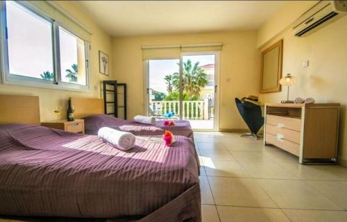 a bedroom with two beds and a desk and windows at Nissi Golden Sand lovely one bedroom apartment with spacious terrace and free parking in Ayia Napa