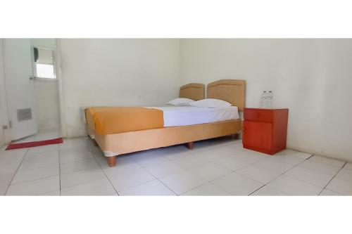 a bedroom with a bed in a white room at Hotel Sri Indrawati Puncak Mitra RedDoorz in Bogor