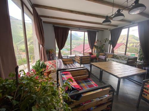 カズベギにあるVeranda Guesthouseのテーブルと椅子と窓のあるリビングルーム