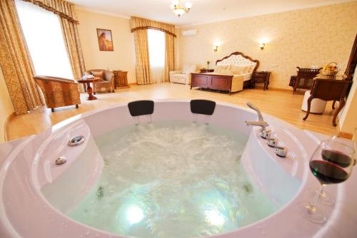 a large white bath tub with two glasses of wine at DiAnna in Skhidnitsa