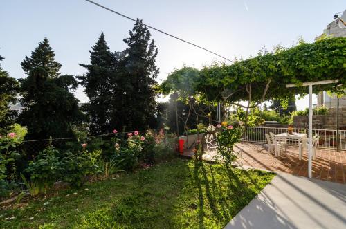 a garden with a fence and a table and flowers at Guest House Curic in Dubrovnik