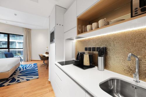 uma cozinha com uma pia e uma cama em um quarto em Adagio Premium The Palm no Dubai