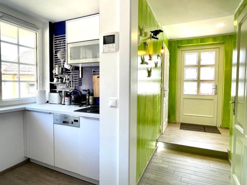 una cucina con armadi bianchi e pareti verdi di Entzückende Garconniere im Herzen Spittals a Spittal an der Drau