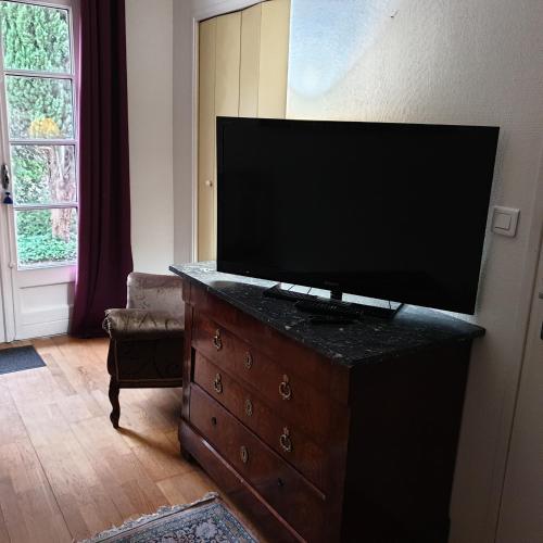 a flat screen tv on a dresser in a living room at Chambre privée dans une maison avec piscine in Tournefeuille