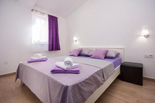 sypialnia z dużym łóżkiem z fioletową pościelą i ręcznikami w obiekcie Apartment Perla w mieście Brodarica
