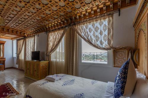 a bedroom with a bed and a window with curtains at Hotel Dar Mounir in Chefchaouen