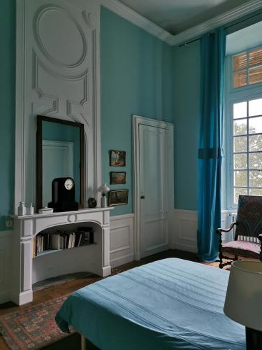 - une chambre avec des murs bleus, un lit et un miroir dans l'établissement Château de Chasseneuil sur Bonnieure, à Chasseneuil-sur-Bonnieure