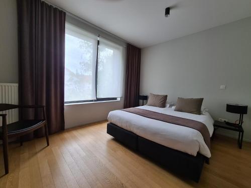 a bedroom with a bed and a large window at B&B A Côté du Cinquantenaire in Brussels