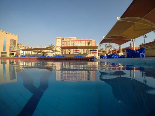 a pool of water with chairs and umbrellas at Rehana Resort in Cairo