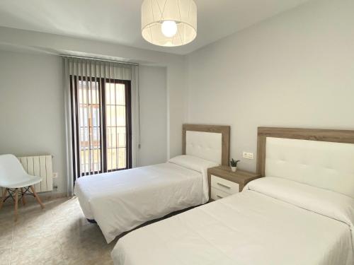 1 dormitorio con 2 camas y lámpara de araña en Apartamento Serranos Centro Histórico, en Salamanca