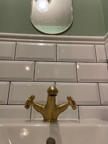 ein Badezimmerwaschbecken mit goldener Armatur und Spiegel in der Unterkunft El Rollo in Molinaseca