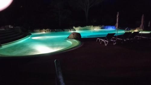 a swimming pool at night with chairs around it at Duplex village vacances Grospierres in Grospierres