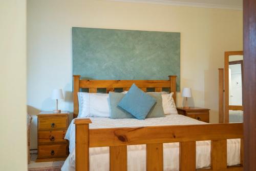 um quarto com uma cama de madeira e almofadas azuis em Linger Longer Vineyard em Willunga