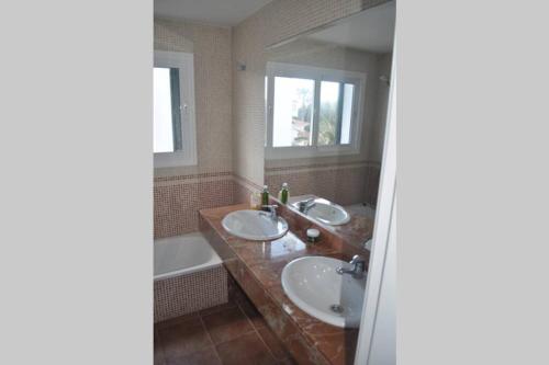 a bathroom with two sinks and a bath tub at Villa Blanca Punta Grossa in Punta Grossa