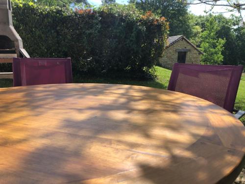 une table en bois et deux chaises dans la cour dans l'établissement Gites Le Pagus, à Simeyrols