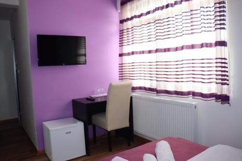 a bedroom with a desk and a purple wall at Restoran & Motel Manjež in Bijelo Polje
