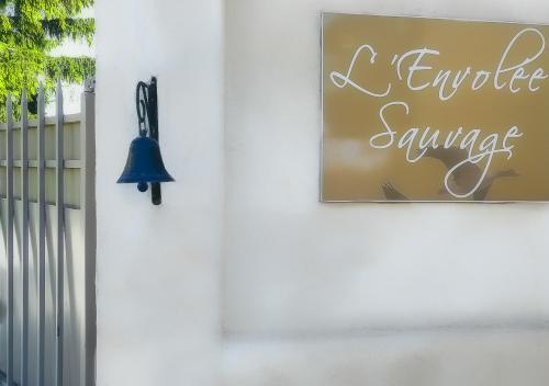 Una campana en una pared con una señal que dice que evalúo los servicios en L'Envolée Sauvage, en Cordes-sur-Ciel