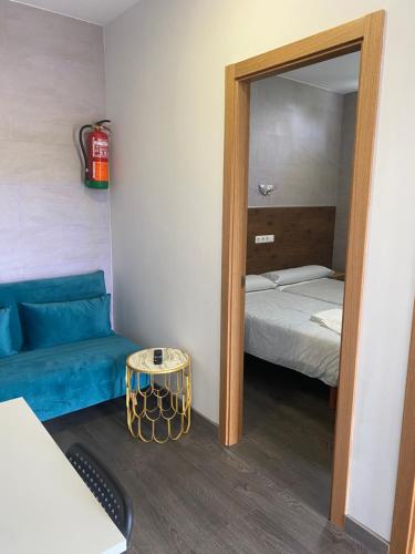a room with a mirror and a bed and a blue couch at A Fontana de Luxo Apartamentos in Portomarin