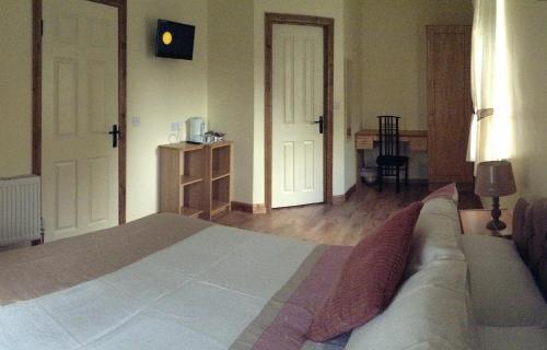 a bedroom with a bed with a couch and two doors at Deerpark Manor Bed and Breakfast in Swinford