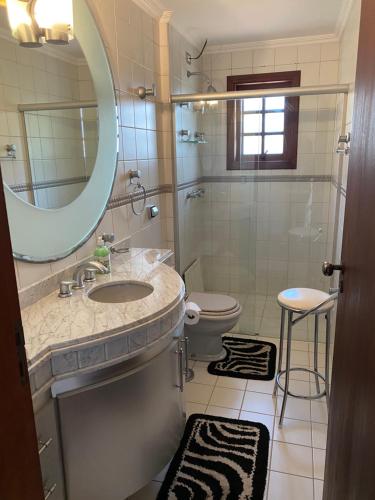 a bathroom with a sink and a toilet and a mirror at Apartamento lindo e aconchegante em Capivari. in Campos do Jordão