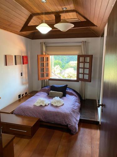 a bedroom with a bed with a table and a window at Apartamento lindo e aconchegante em Capivari. in Campos do Jordão