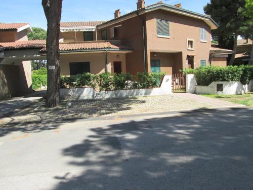 uma casa com uma árvore em frente a uma entrada em Giannella Appartamenti em Orbetello