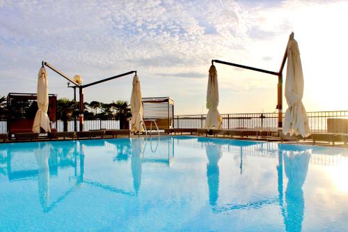 een groot zwembad met witte parasols bij BO Hotel Palazzo in Poreč