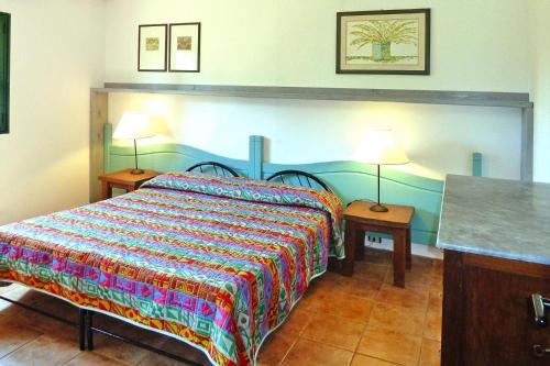 a bedroom with a bed with a colorfulspread and two lamps at Apartment in Guardistallo with heating in Guardistallo