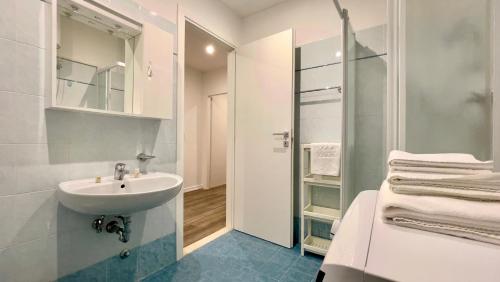 a white bathroom with a sink and a shower at Monaco Apartments in Lignano Sabbiadoro